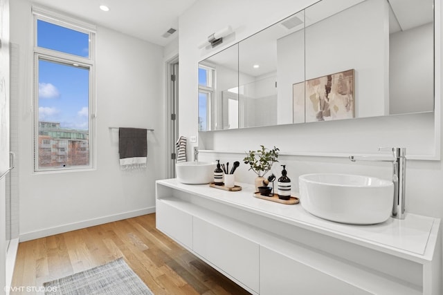 bathroom with wood finished floors, a sink, visible vents, and baseboards