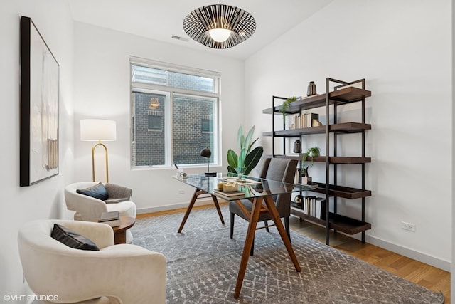 office space with lofted ceiling, baseboards, and wood finished floors