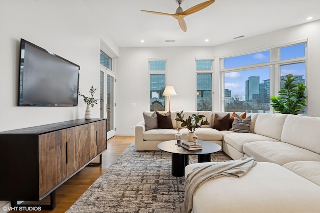 living area featuring dark wood-style flooring, recessed lighting, visible vents, and a city view