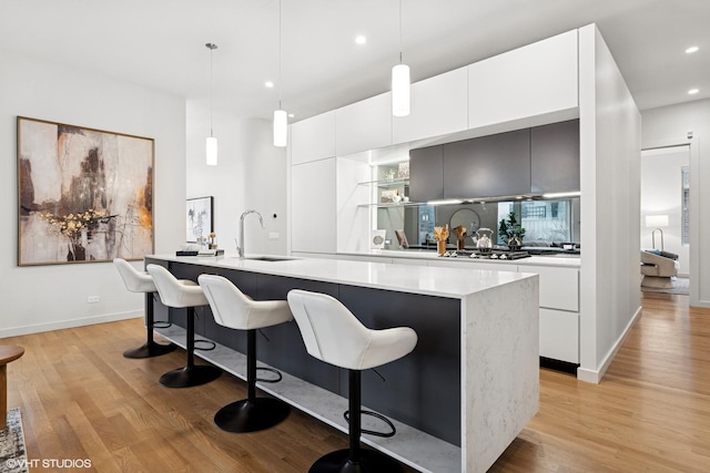 kitchen with a breakfast bar, light wood-type flooring, white cabinetry, and modern cabinets