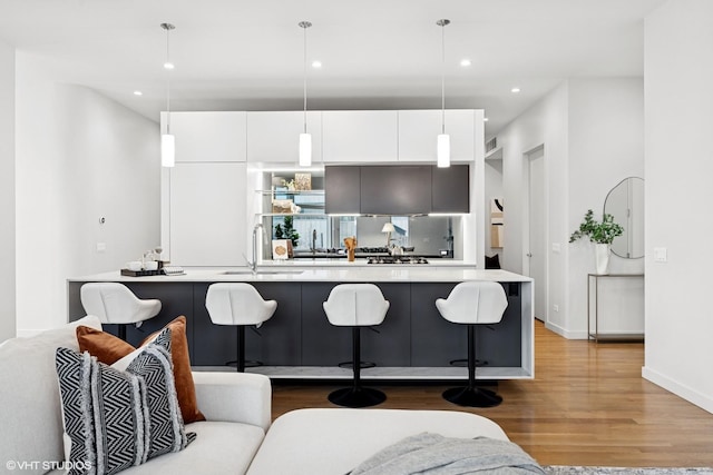 kitchen with modern cabinets, wood finished floors, white cabinetry, and a kitchen breakfast bar