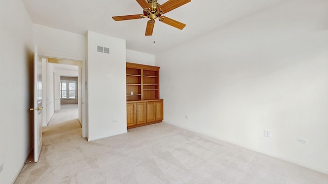 spare room featuring a ceiling fan, light carpet, and visible vents