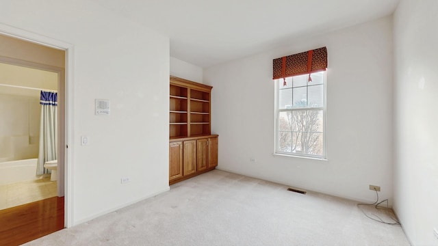 spare room with visible vents and light colored carpet