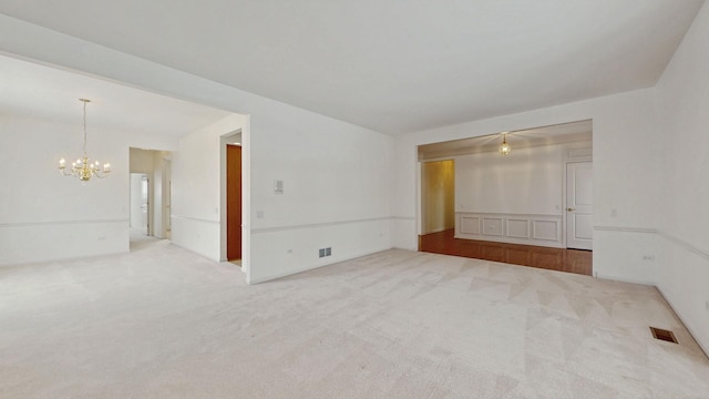 empty room featuring carpet floors, visible vents, and a notable chandelier