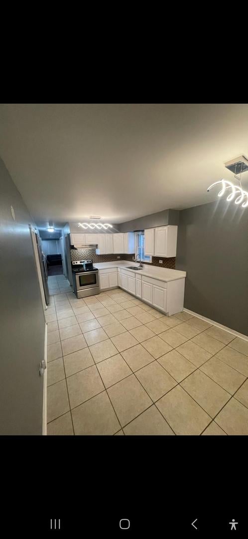 kitchen featuring white cabinetry, electric stove, sink, tasteful backsplash, and light tile patterned flooring