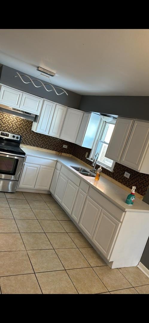 kitchen with white cabinetry, sink, stainless steel range with electric stovetop, light tile patterned flooring, and decorative backsplash