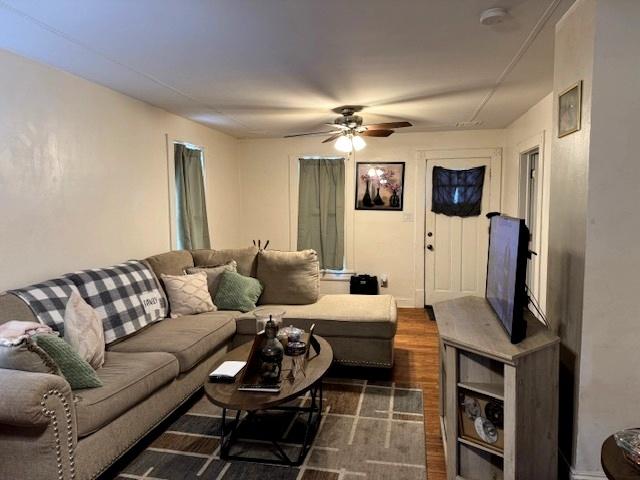 living room featuring ceiling fan and dark wood-type flooring