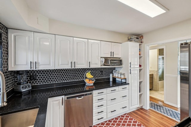 kitchen featuring light wood-style flooring, a toaster, appliances with stainless steel finishes, white cabinetry, and tasteful backsplash