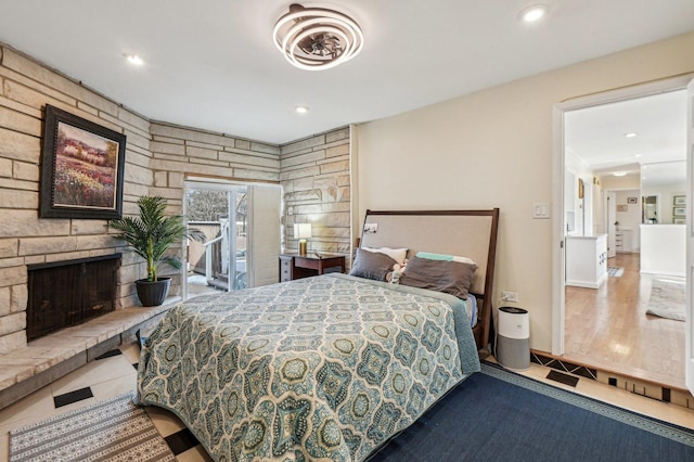 tiled bedroom featuring a stone fireplace and recessed lighting