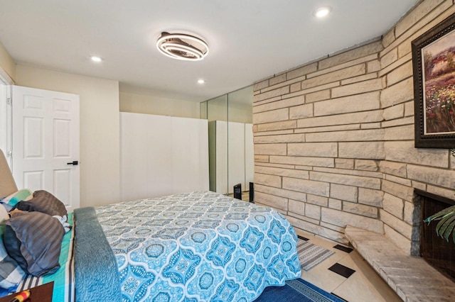 bedroom featuring a closet, a stone fireplace, and recessed lighting