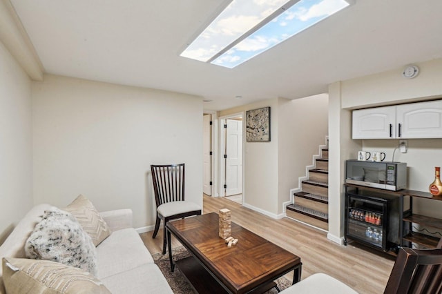 living area featuring stairs, baseboards, and light wood finished floors