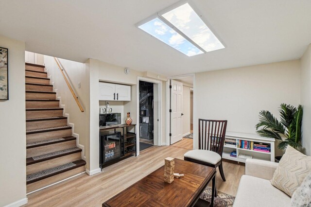 living room with a skylight, stairs, and light wood-style floors