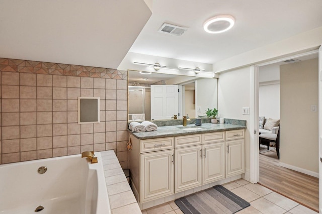 full bath with visible vents, a tub to relax in, vanity, and tile patterned flooring