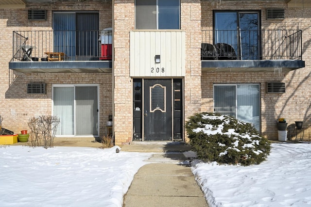 snow covered property entrance with a balcony