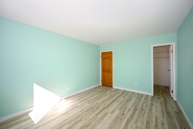 unfurnished bedroom with a closet, a walk in closet, and light hardwood / wood-style flooring