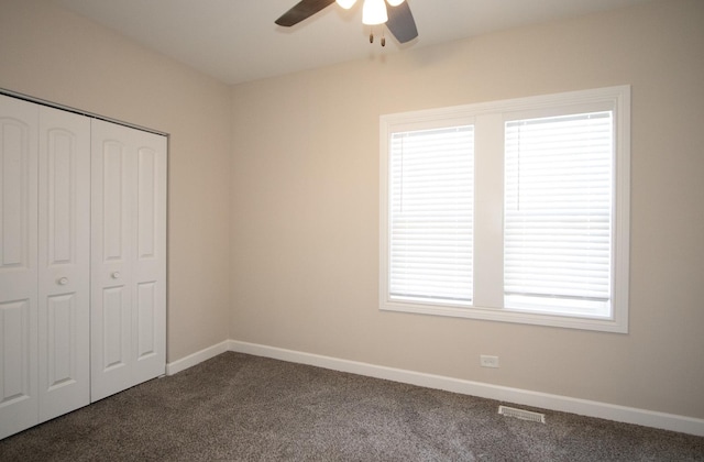 unfurnished bedroom with a ceiling fan, a closet, dark carpet, and baseboards