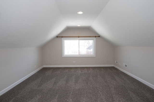 additional living space with recessed lighting, visible vents, dark carpet, vaulted ceiling, and baseboards