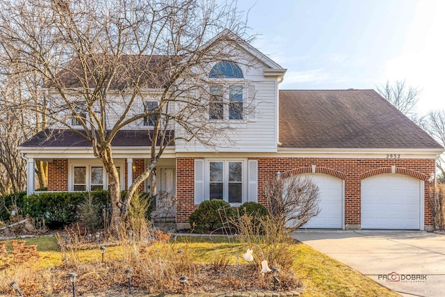 traditional home with a shingled roof, brick siding, driveway, and an attached garage