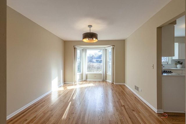 unfurnished dining area with light wood-style floors, visible vents, and baseboards