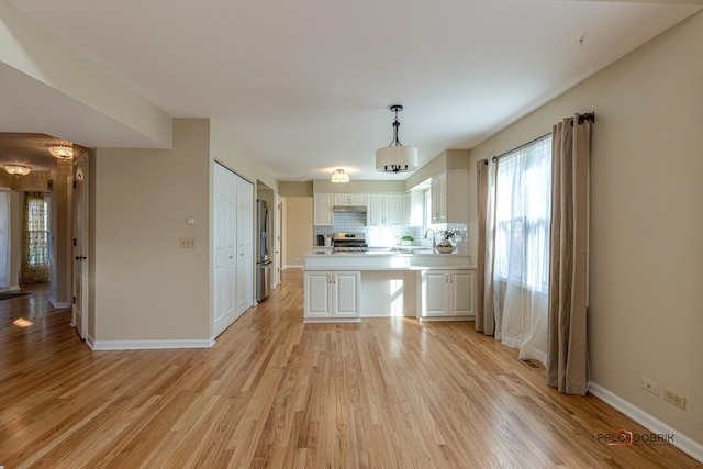 kitchen with light wood finished floors, light countertops, appliances with stainless steel finishes, and white cabinets