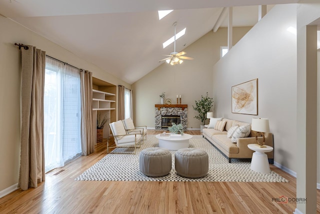 living room featuring plenty of natural light, a skylight, a fireplace, and wood finished floors