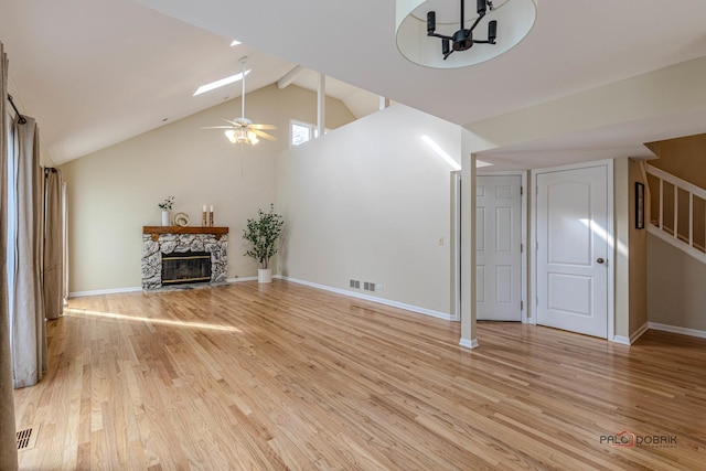 unfurnished living room with a ceiling fan, light wood-type flooring, a stone fireplace, and baseboards