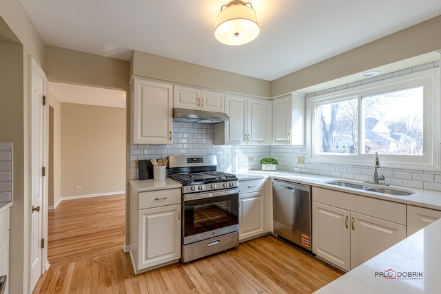 kitchen featuring light countertops, appliances with stainless steel finishes, a sink, and under cabinet range hood