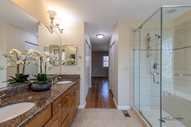 full bathroom featuring tile patterned flooring, a sink, a shower stall, and double vanity