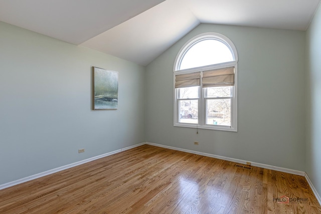 empty room featuring lofted ceiling, wood finished floors, visible vents, and baseboards