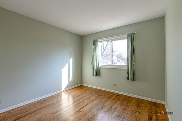 empty room with visible vents, baseboards, and wood finished floors