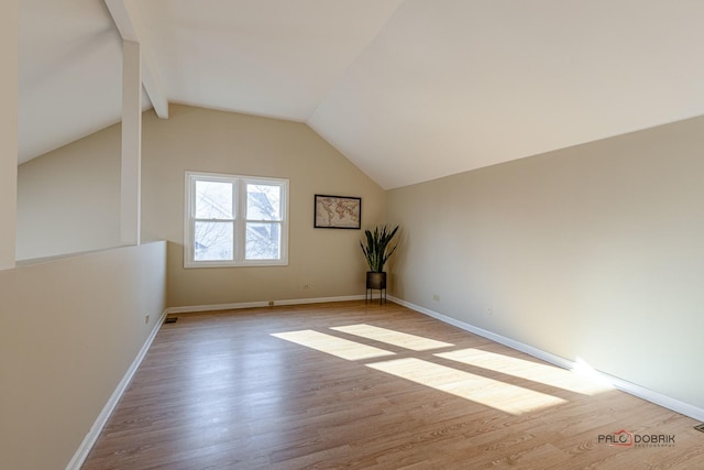 bonus room featuring lofted ceiling with beams, baseboards, and wood finished floors