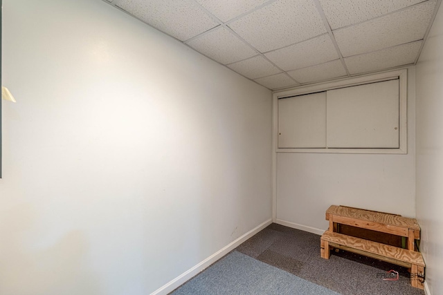 unfurnished bedroom featuring carpet floors, a paneled ceiling, and baseboards