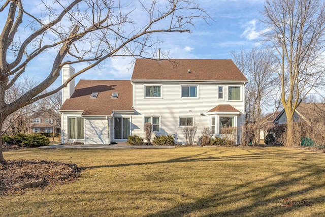 rear view of house featuring a shingled roof, a yard, and a chimney