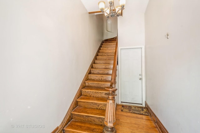 stairs featuring hardwood / wood-style floors and a chandelier