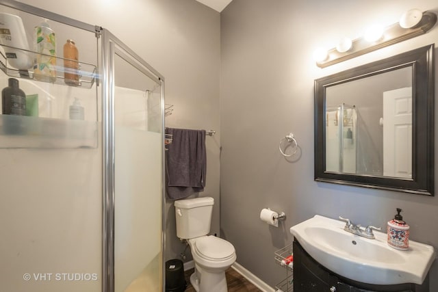 bathroom featuring vanity, toilet, and a shower with shower door