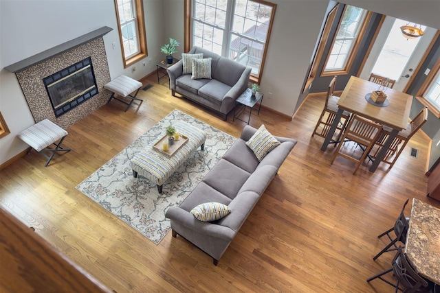 living area with visible vents, a fireplace, baseboards, and wood finished floors