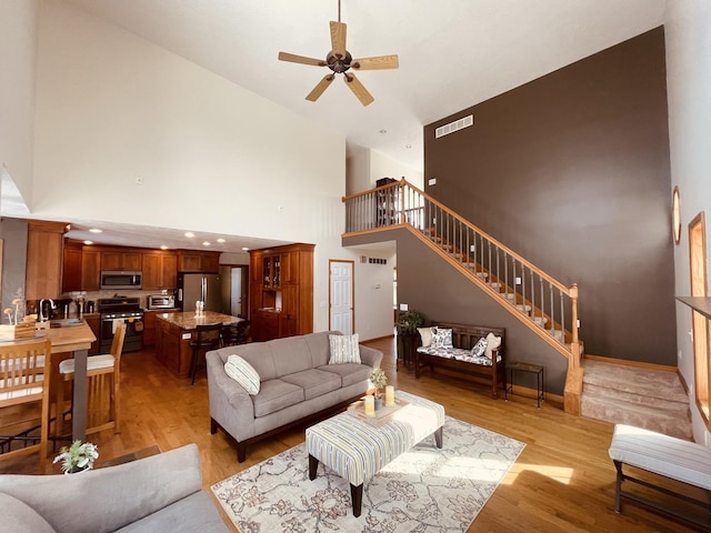 living area featuring recessed lighting, visible vents, baseboards, stairs, and light wood finished floors