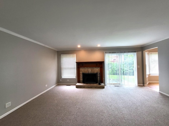 unfurnished living room featuring carpet flooring, a brick fireplace, crown molding, and a wealth of natural light