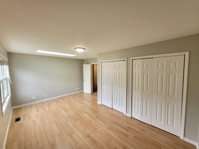 unfurnished bedroom featuring light hardwood / wood-style floors and multiple closets