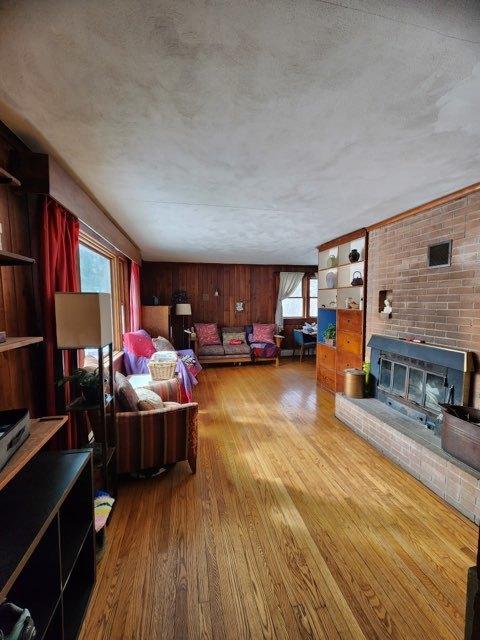 living area with a fireplace, wood walls, and light wood-style flooring