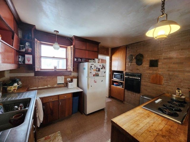 kitchen featuring light countertops, stainless steel microwave, freestanding refrigerator, and decorative light fixtures