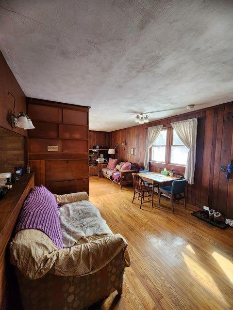 interior space featuring light wood-style floors, wood walls, and a textured ceiling