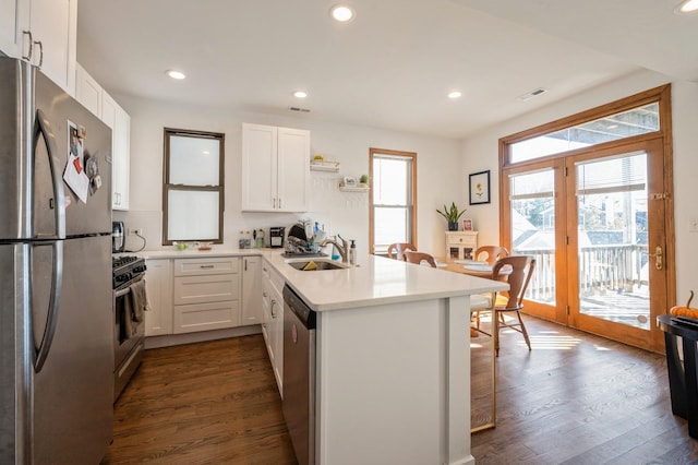 kitchen featuring a peninsula, a sink, white cabinets, light countertops, and appliances with stainless steel finishes