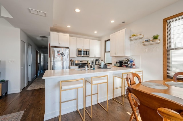 kitchen with visible vents, light countertops, appliances with stainless steel finishes, white cabinets, and a peninsula