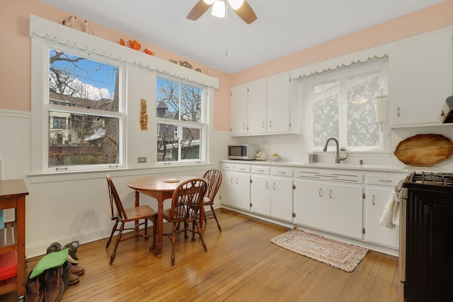 kitchen with light wood-type flooring, white microwave, gas stove, and white cabinets