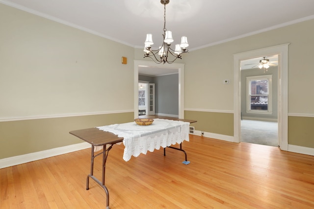 dining space with baseboards, ornamental molding, an inviting chandelier, and light wood-style floors