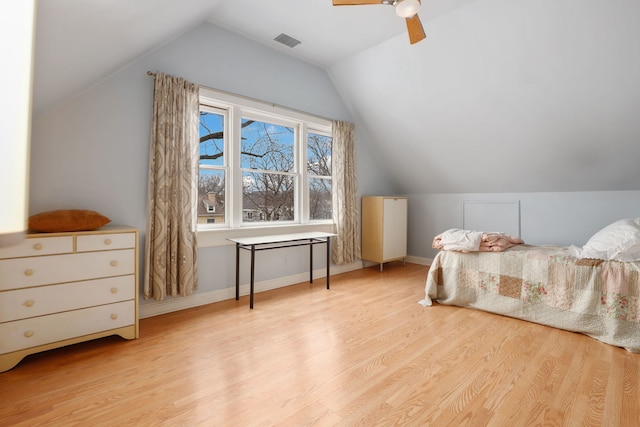 bedroom featuring baseboards, visible vents, vaulted ceiling, and wood finished floors