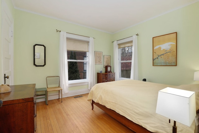 bedroom featuring ornamental molding, light wood-type flooring, and baseboards