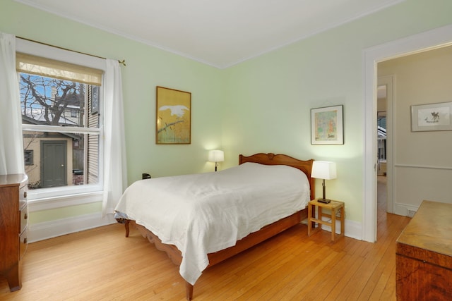 bedroom featuring light wood-style floors, baseboards, and crown molding