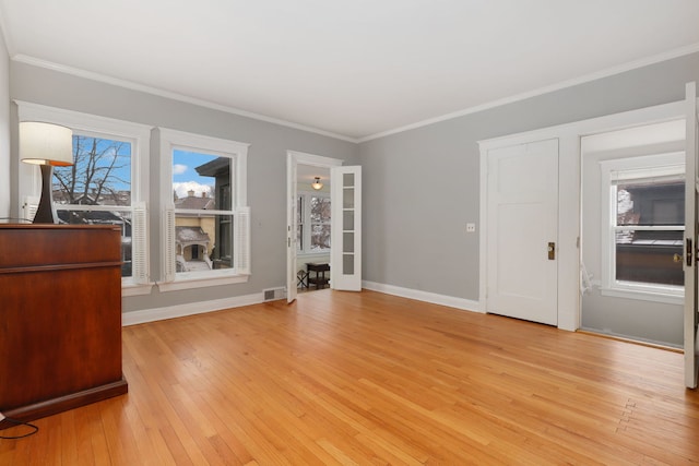 unfurnished living room featuring ornamental molding, light wood finished floors, plenty of natural light, and baseboards